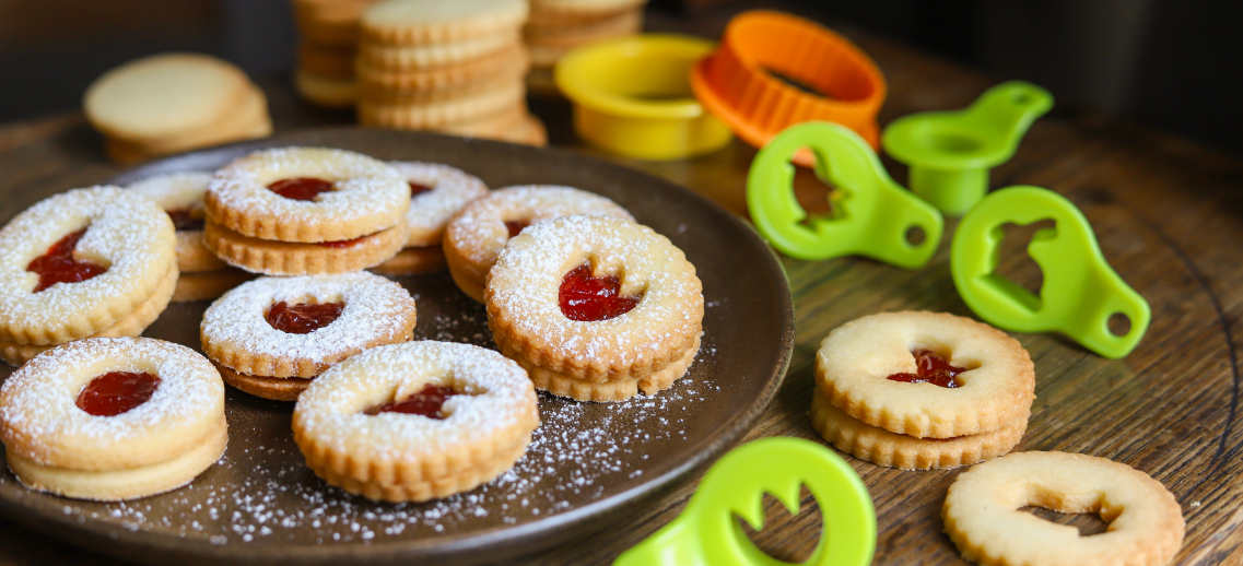 Kruche ciasteczka z nadzieniem z marmolady, w tle wykrawacze w wielkanocnych kształtach.