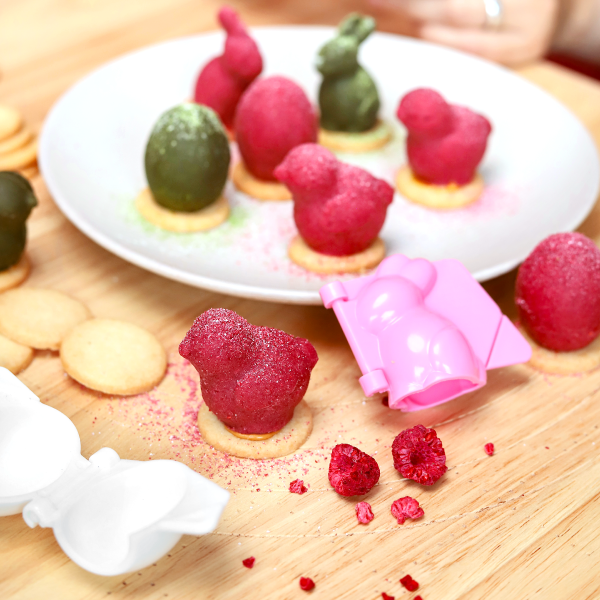 Ciemnoróżowe nadziewane ciasteczko w kształcie pisklaczka, obok otwierana plastikowa foremka w tym samym kształcie.