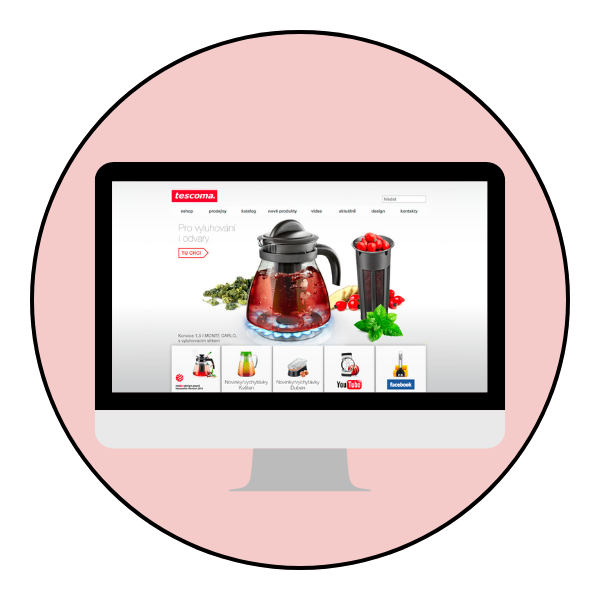 Grafika przedstawia monitor komputera, na którym wyświetla się strona główna Tescomy. Monitor stoi na jasnoróżowym tle.