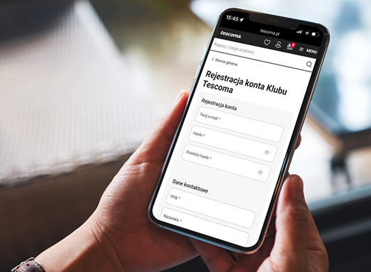 Osoba trzyma smartfon, na którego ekranie wyświetla się strona rejestracji w Klubie TESCOMA.