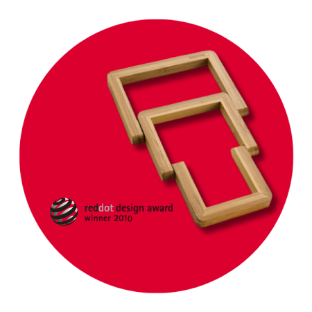 Opis: grafika przedstawia drewnianą rozkładaną podstawkę ONLINE na czerwonym tle. Obok podstawki widnieje informacja o tym, że produkt wygrał nagrodę reddot design award w 2010 roku.